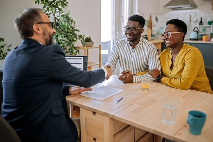 Black business owners sitting at a table shaking hands with banker