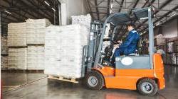 A man on a forklift works in a large warehouse