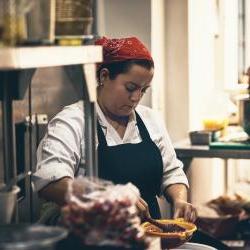Hispanic woman wearing read bandana over hair in restaurant kitchen